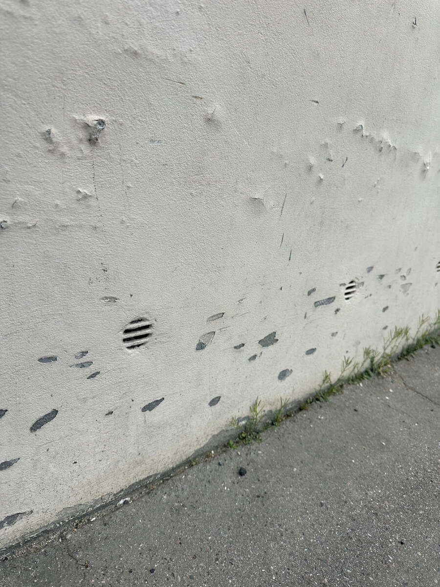 Enduit de façade cloqué et décollé par plaques en partie basse d'un mur ancien